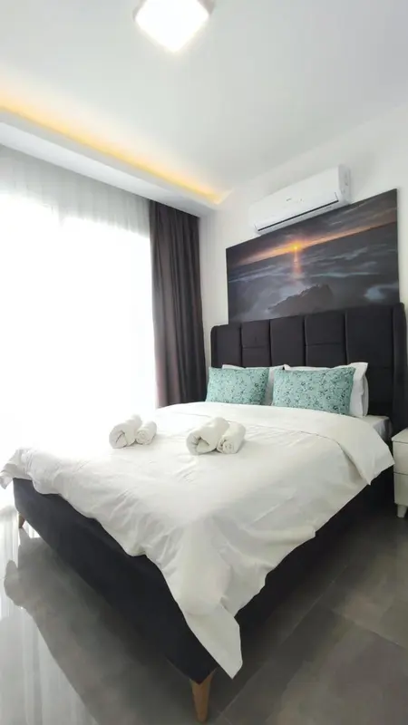 Une chambre lumineuse avec un grand lit recouvert de draps blancs et de coussins verts.