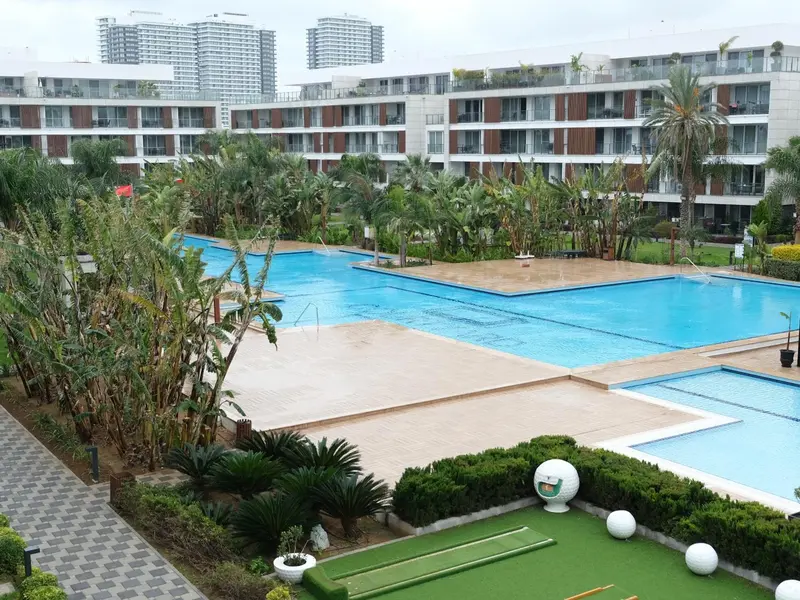 Vue aérienne d'un complexe hôtelier avec piscine et végétation tropicale.