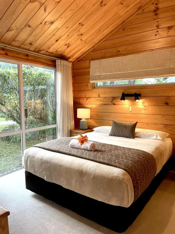 Une chambre lumineuse avec un grand lit et une vue sur la végétation.