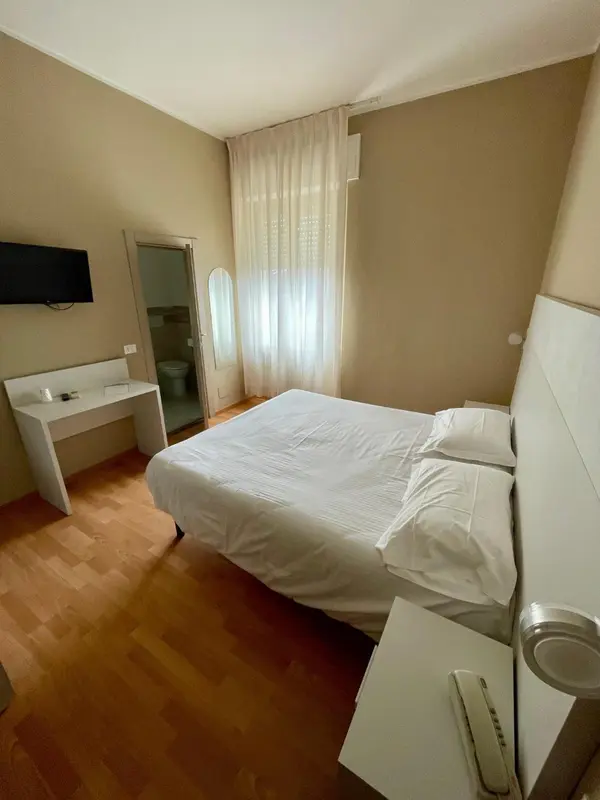 Chambre lumineuse avec un lit simple et un bureau blanc.