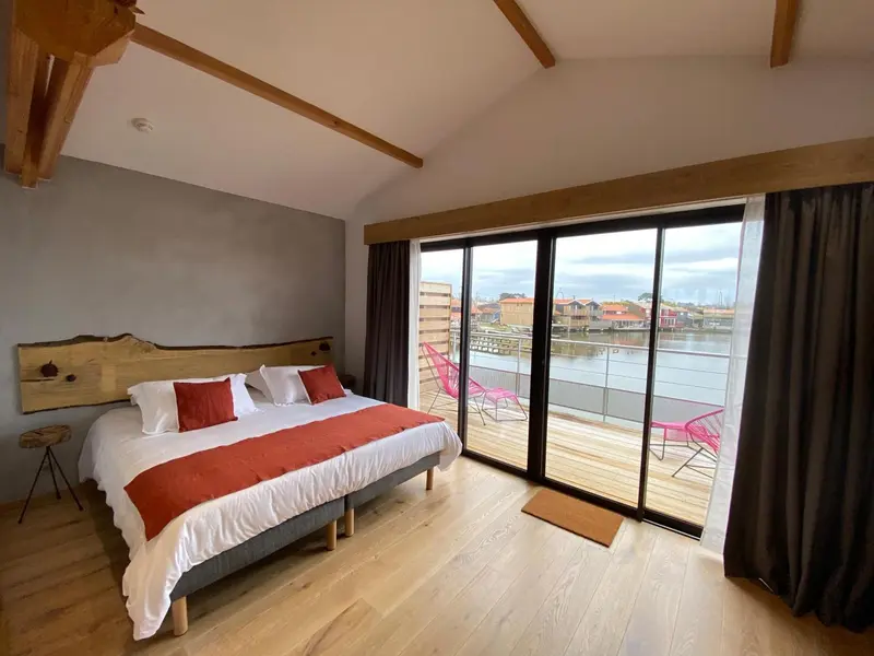 Chambre lumineuse avec un grand lit et une vue sur un port de plaisance.