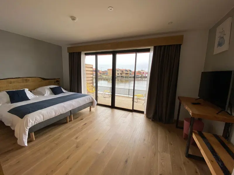 Une chambre lumineuse avec un grand lit donnant sur une terrasse et un plan d'eau.