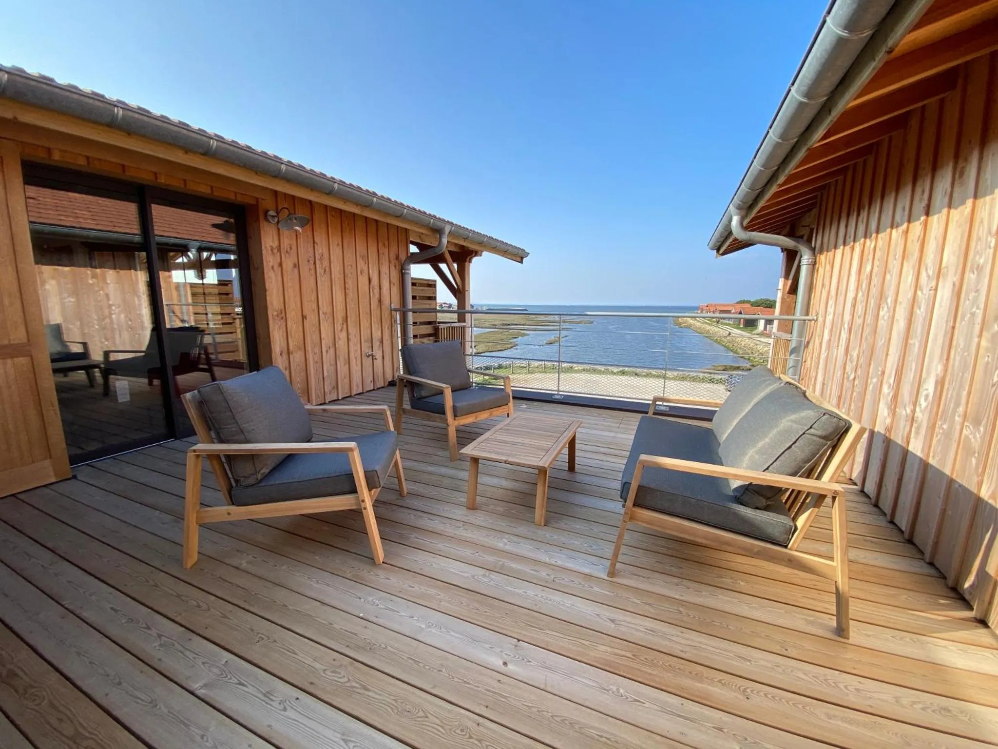 Terrasse en bois avec mobilier de jardin et vue sur la mer.