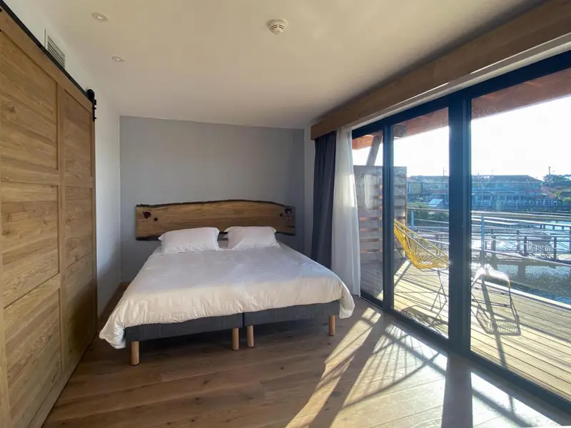 Une chambre lumineuse avec un grand lit et un accès à une terrasse ensoleillée.