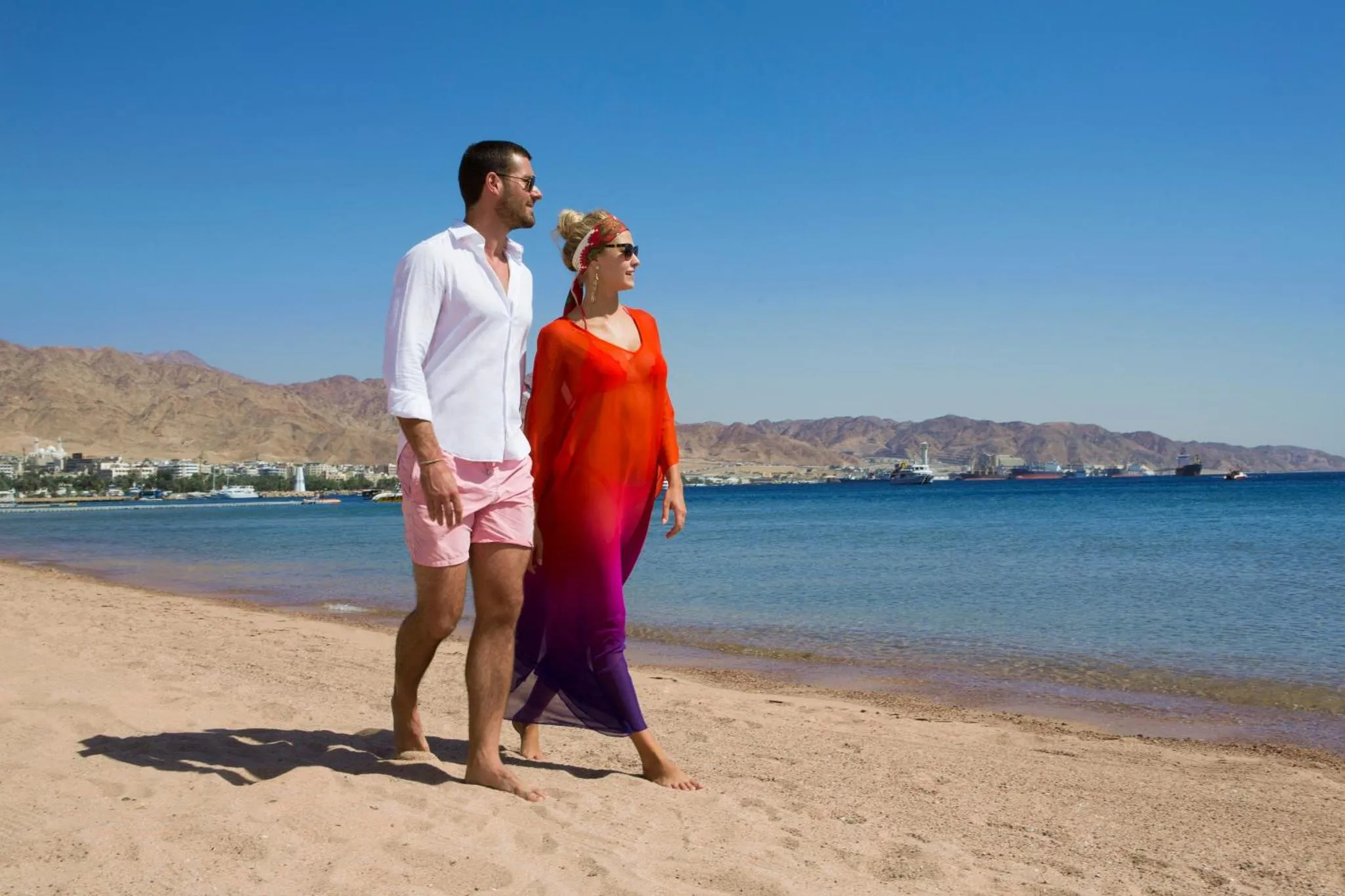 Un couple se promène sur une plage de sable fin face à la mer.