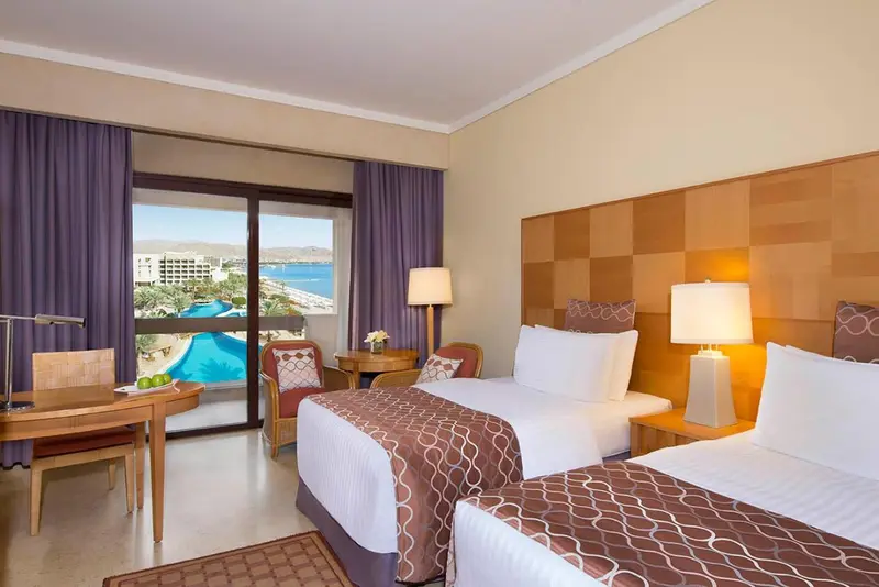 Chambre lumineuse avec un grand lit et vue sur la mer.