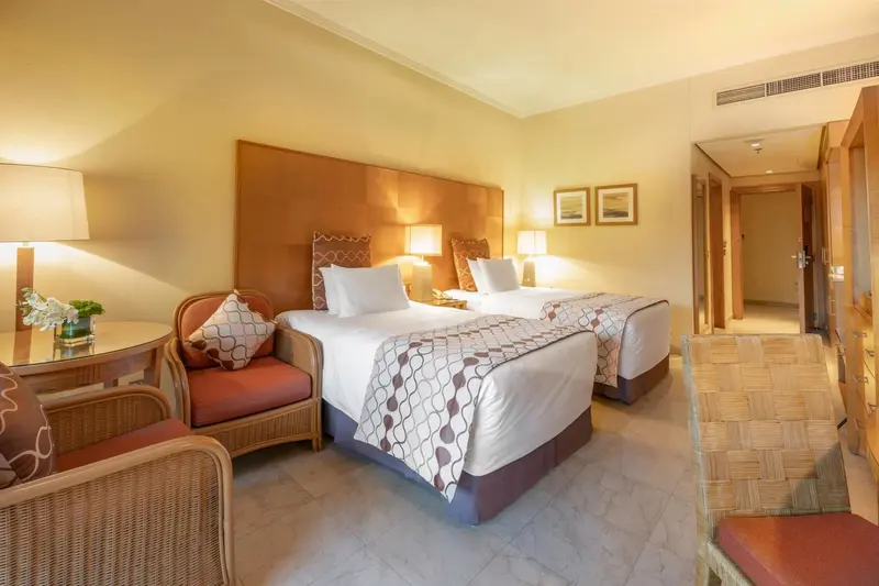 Une chambre lumineuse avec deux lits simples et un coin salon.