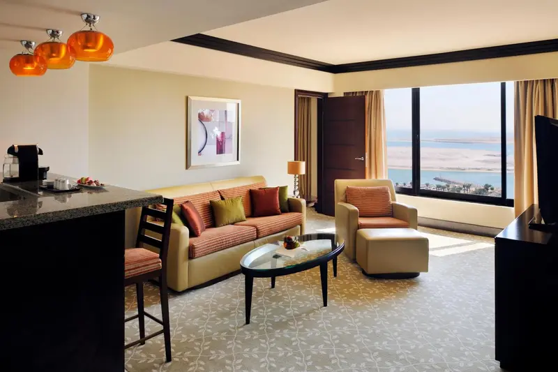 Espace de séjour lumineux avec canapé, fauteuil et vue sur la mer.