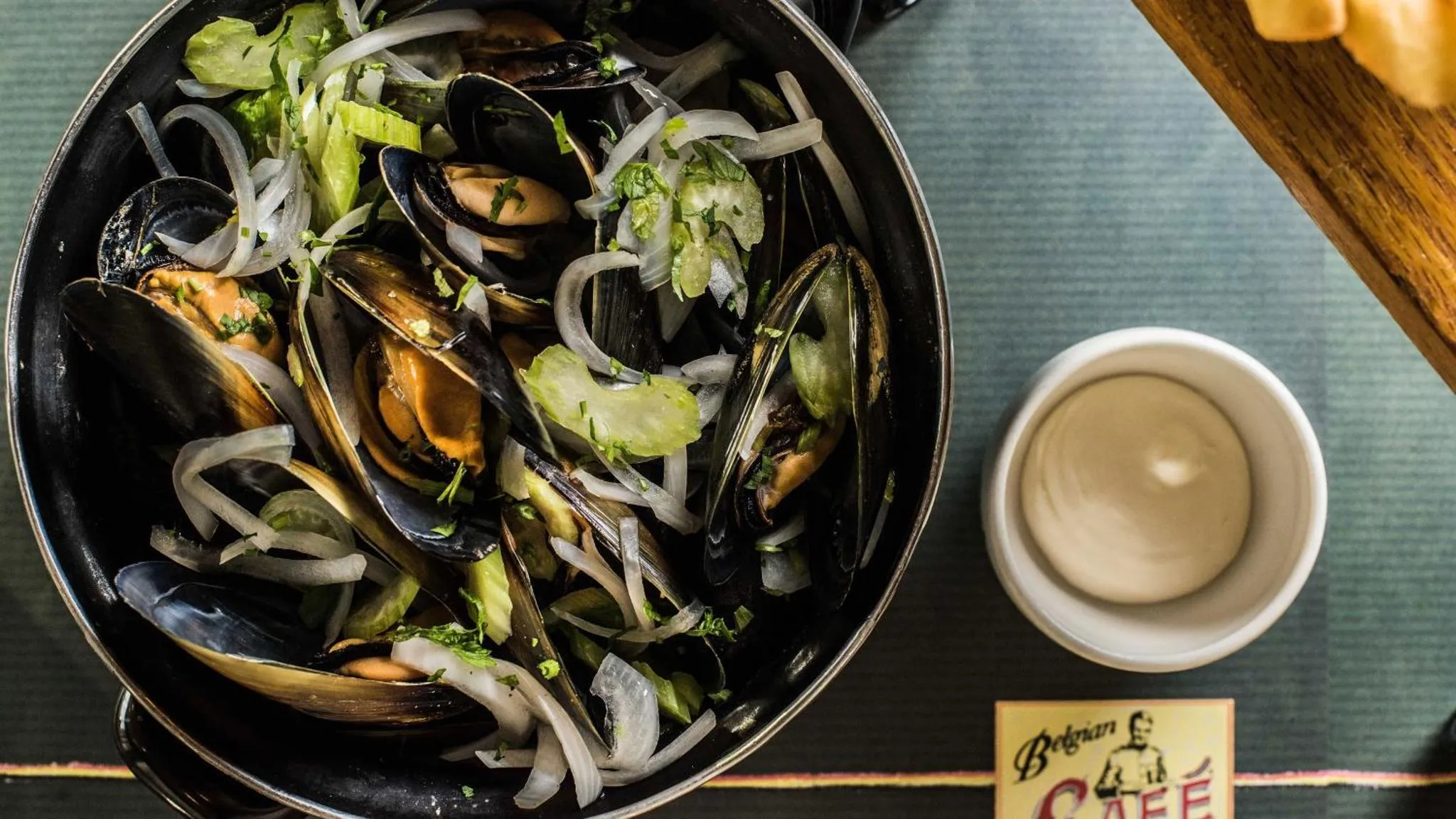 Une portion de moules cuisinées est servie dans une poêle noire avec une sauce à la crème.