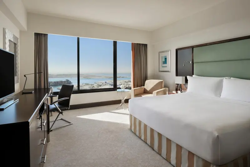 Chambre lumineuse avec un grand lit et une vue sur la mer.
