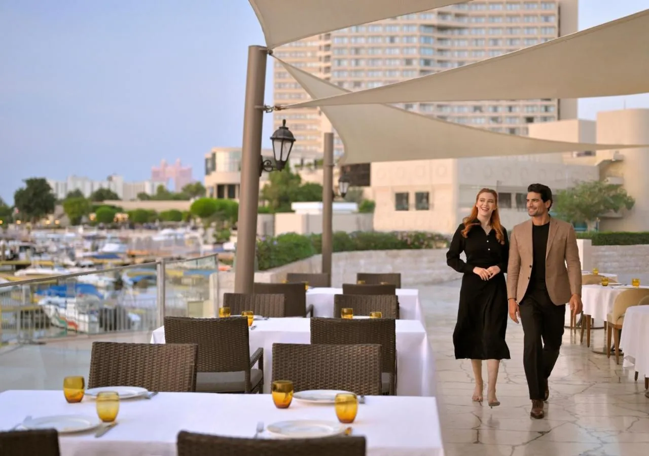 Un couple se promène sur une terrasse de restaurant en bord de mer.