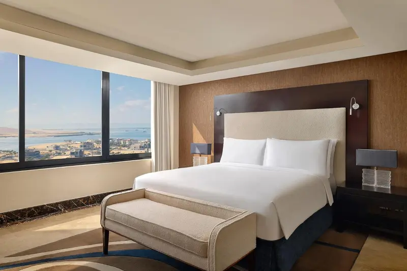 Chambre lumineuse avec un grand lit et une vue sur la mer.