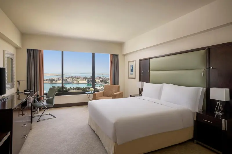 Chambre lumineuse avec un grand lit et une vue sur la mer.