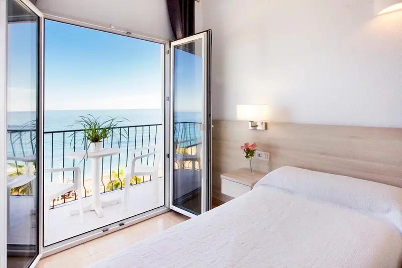 Chambre lumineuse avec balcon donnant sur la mer.