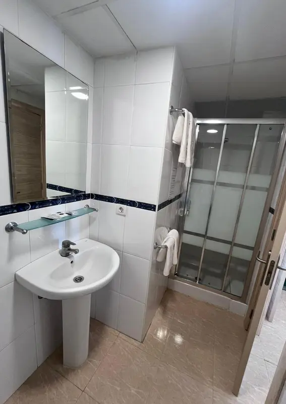 Une salle de bain claire avec douche et lavabo.