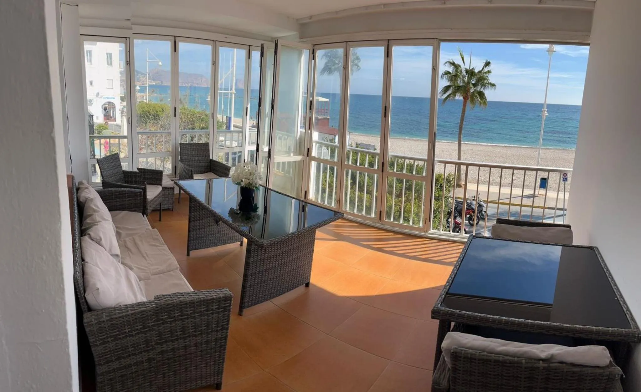 Espace de détente avec mobilier en rotin et vue sur la mer.