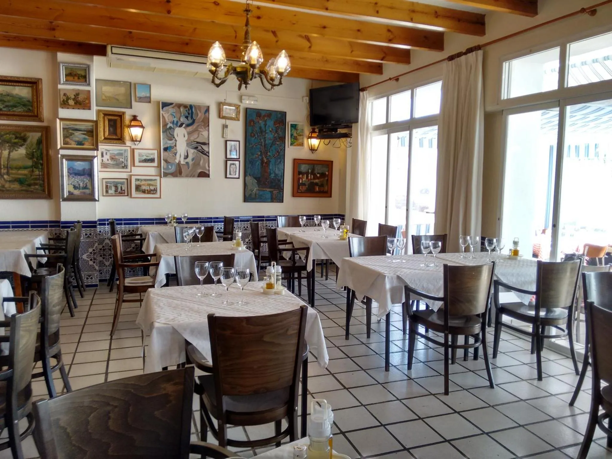 Une salle lumineuse avec des tables dressées pour un repas.
