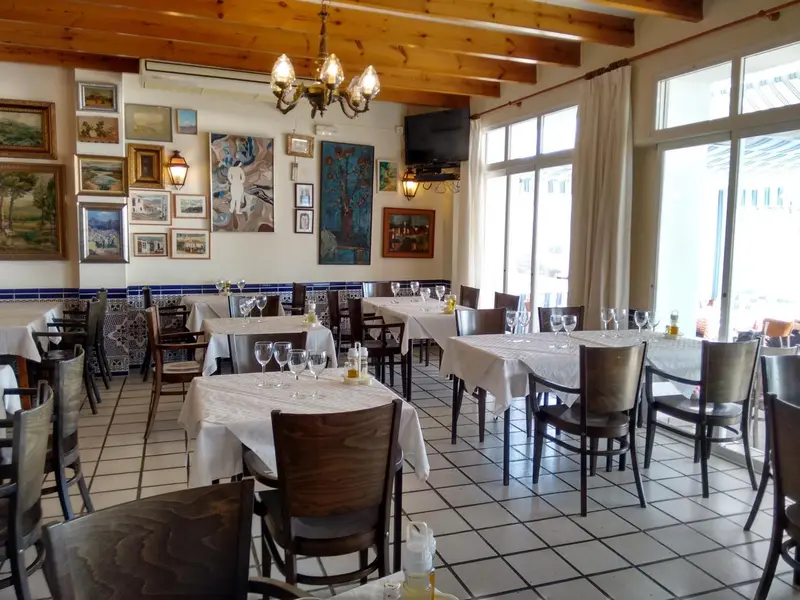 Une salle lumineuse avec des tables dressées pour un repas.