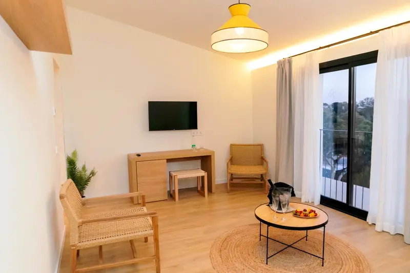 Une chambre lumineuse avec un bureau et un coin salon.