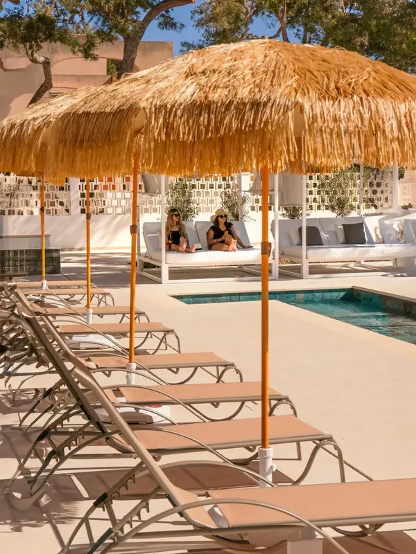Transats et parasols ombragent une terrasse avec une piscine au premier plan.