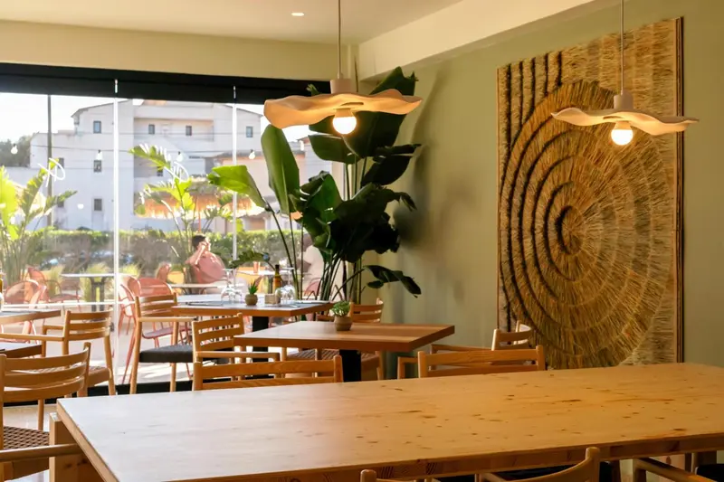 Une salle lumineuse avec des tables en bois et des suspensions décoratives.