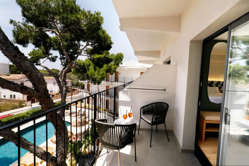 Une terrasse avec deux fauteuils et une table basse donnant sur une piscine et un paysage verdoyant.