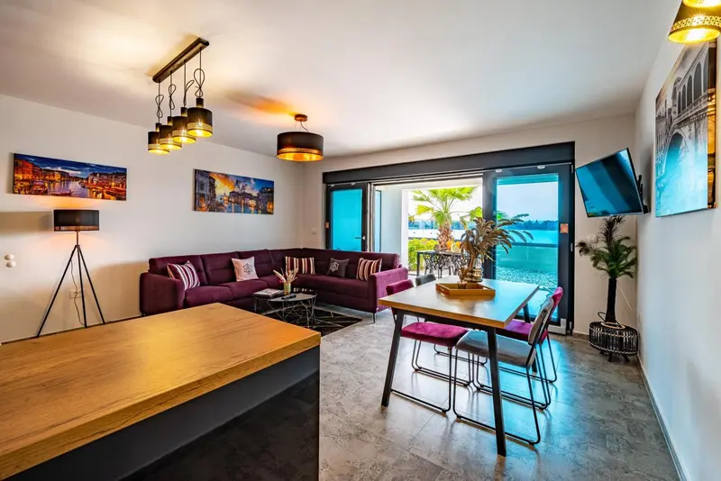 Un salon moderne avec canapé pourpre et table basse donne sur une vue dégagée sur la mer.