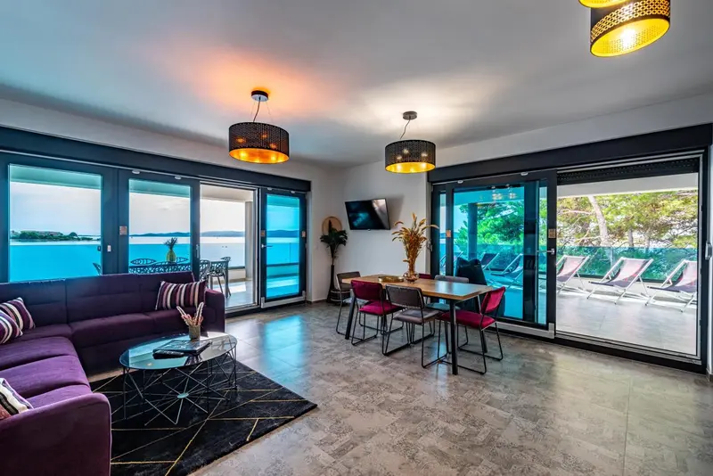 Un salon moderne s'ouvre sur une terrasse avec vue sur la mer.
