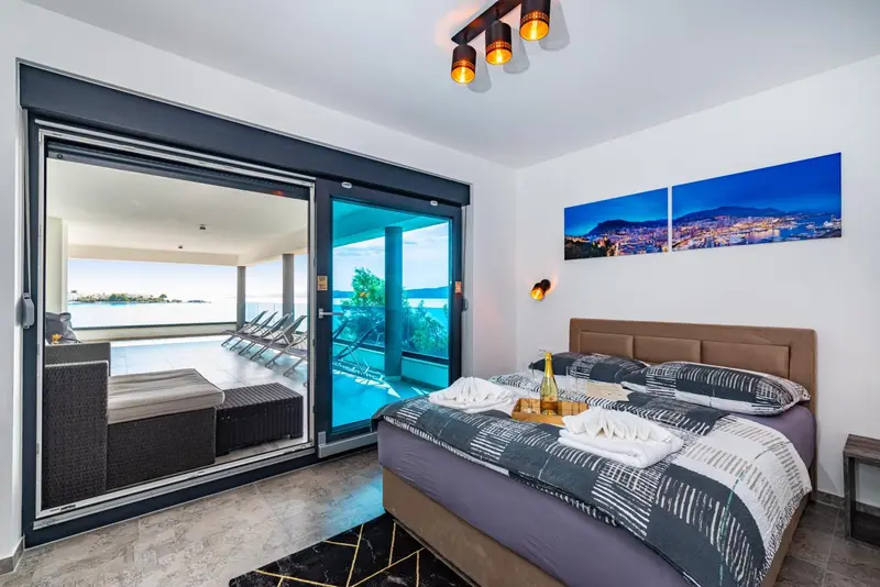 Une chambre avec un grand lit donnant sur une terrasse et la mer.