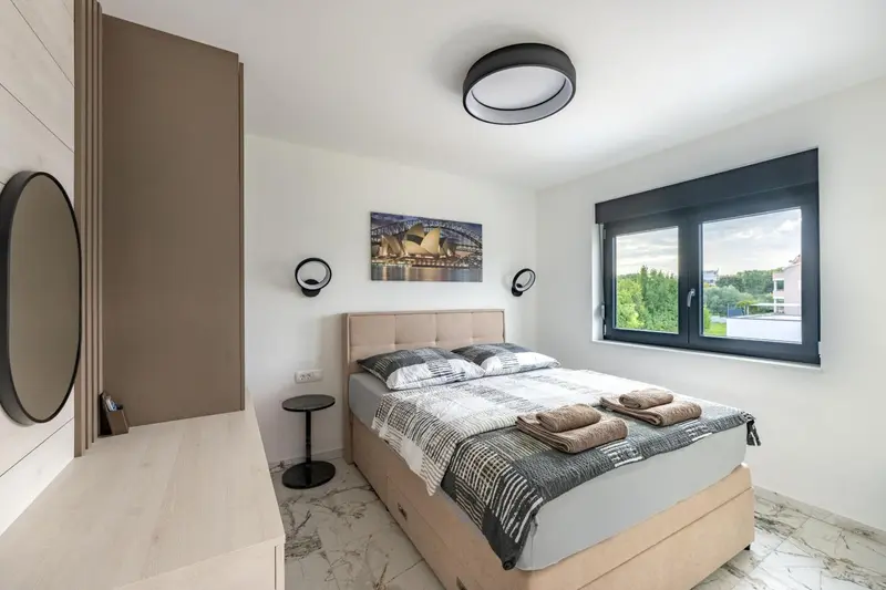 Une chambre lumineuse avec un grand lit et une fenêtre donnant sur un paysage.