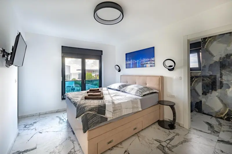 Une chambre lumineuse avec un grand lit et un accès à une terrasse.
