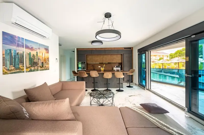 Espace de vie moderne avec canapé, bar et vue sur l'extérieur.