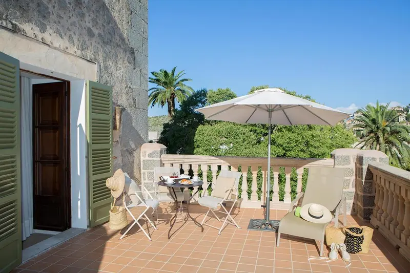 Une table avec des couverts est mise en scène sur une terrasse ensoleillée.