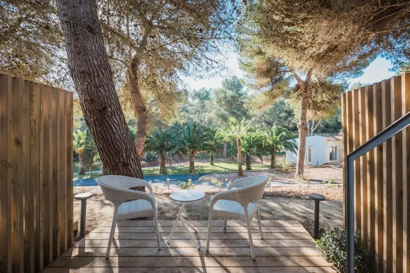 Deux fauteuils et une table basse sur une terrasse en bois.
