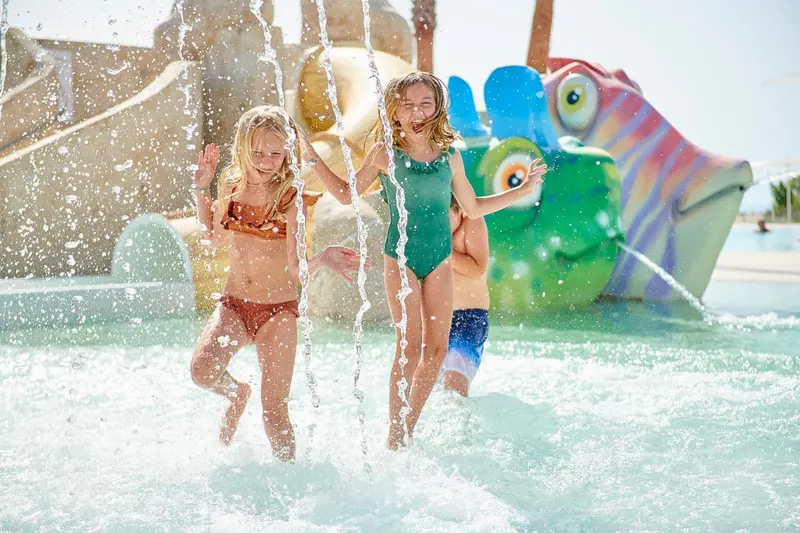 Des enfants s'amusent sous une structure aquatique colorée.