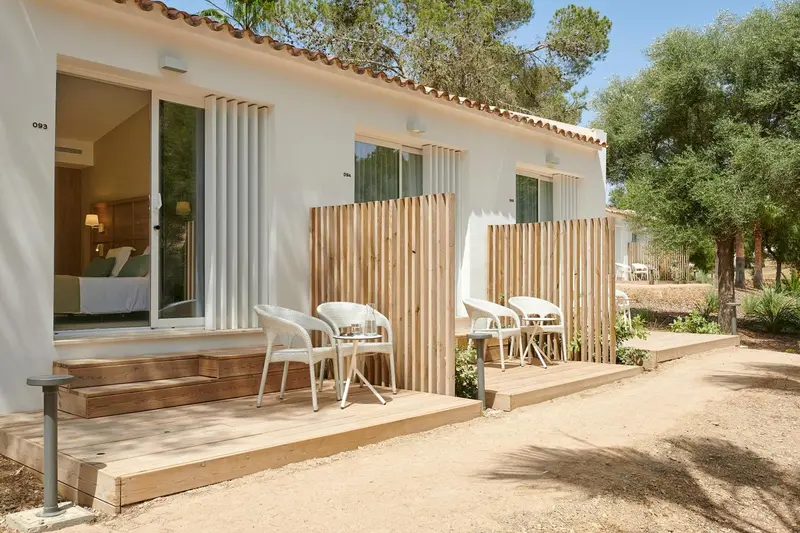 Terrasse en bois devant un logement blanc avec des fauteuils.