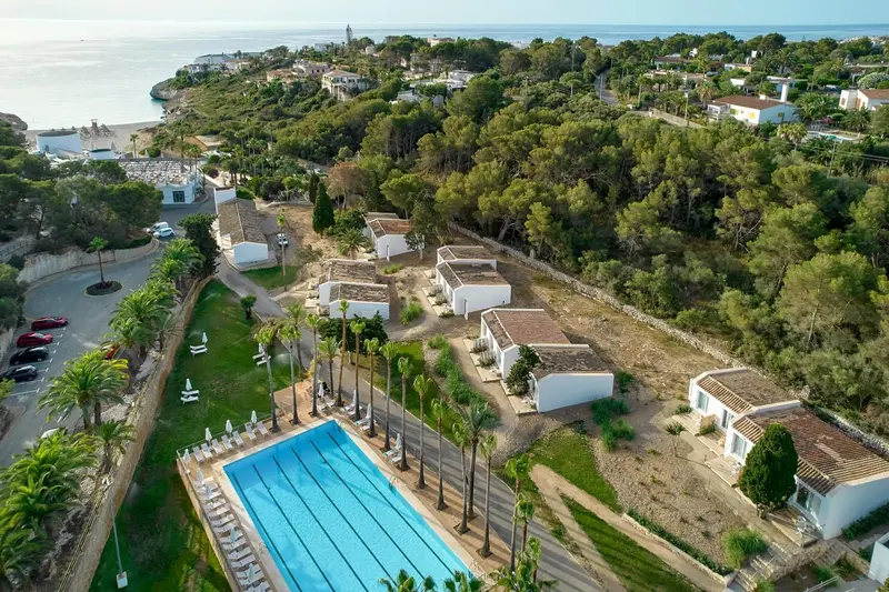 Vue aérienne d'un complexe hôtelier avec piscine et végétation luxuriante.