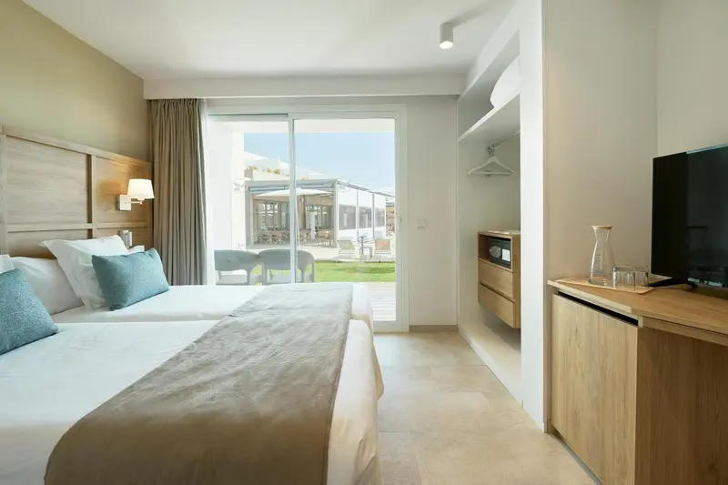 Une chambre lumineuse avec un grand lit et un accès à une terrasse.