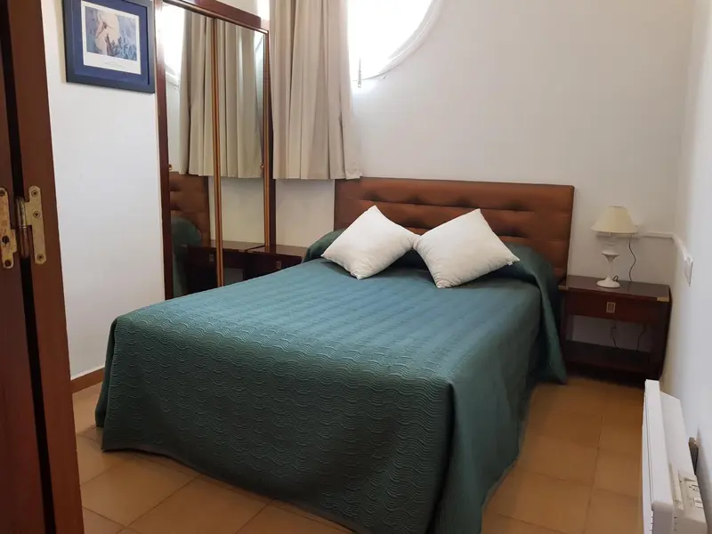 Une chambre avec un lit recouvert d'une couverture verte et des meubles en bois.