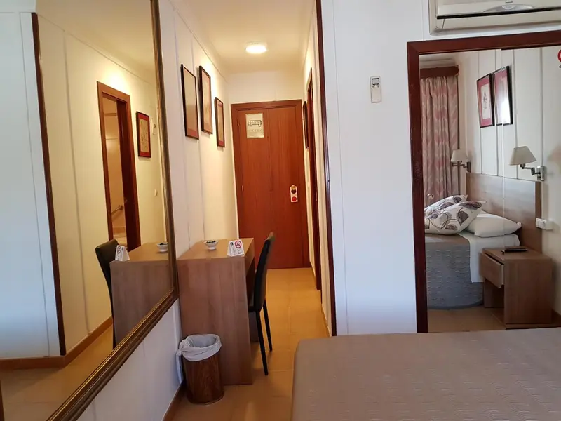 Une entrée d'appartement mène à une chambre avec un lit et des tableaux.