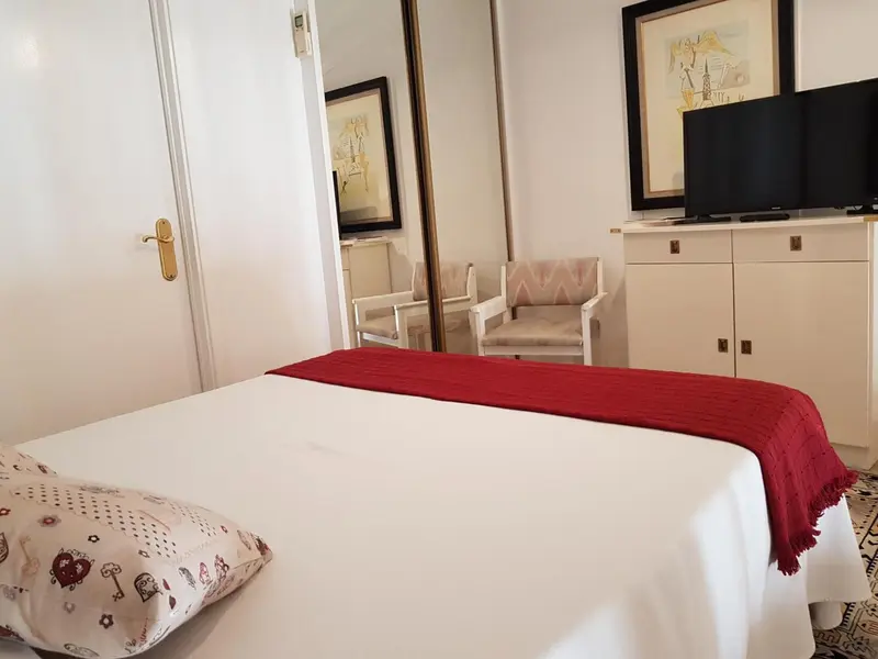 Une chambre lumineuse avec un lit recouvert d'une courtepointe rouge.