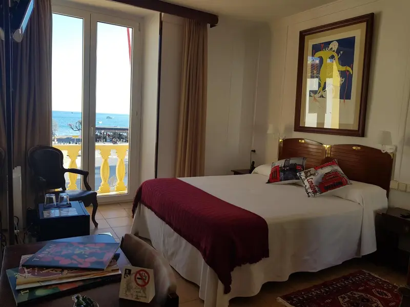 Une chambre lumineuse avec un lit et un accès à un balcon donnant sur la mer.