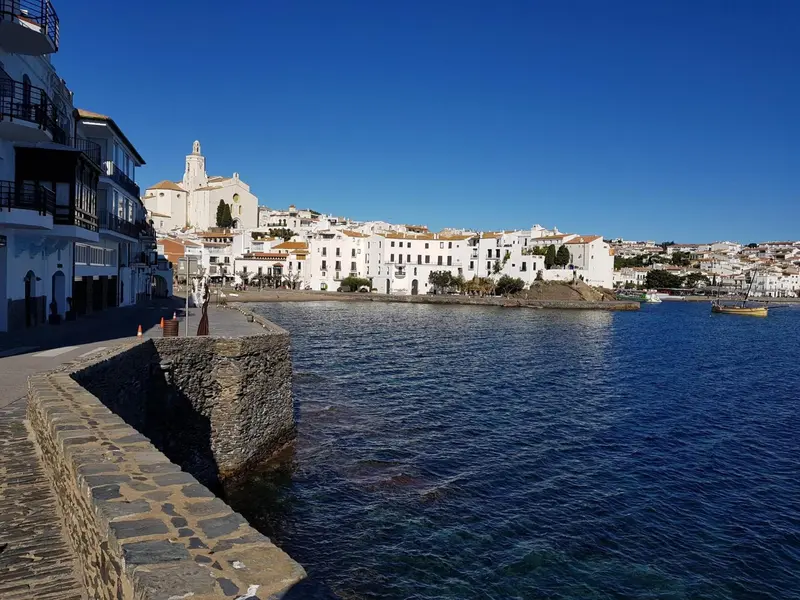 Vue d'un port de plaisance avec des bâtiments blancs et une eau calme.