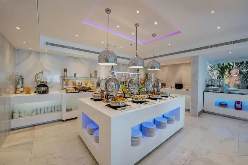 Un buffet propose une variété de plats et de boissons dans un espace lumineux et moderne.