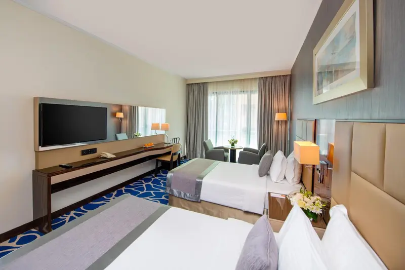 Chambre d'hôtel moderne avec un grand lit et un téléviseur mural.