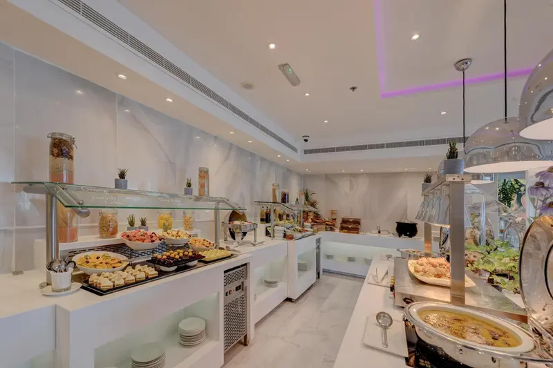 Un buffet propose une variété de plats et de desserts dans une salle lumineuse.