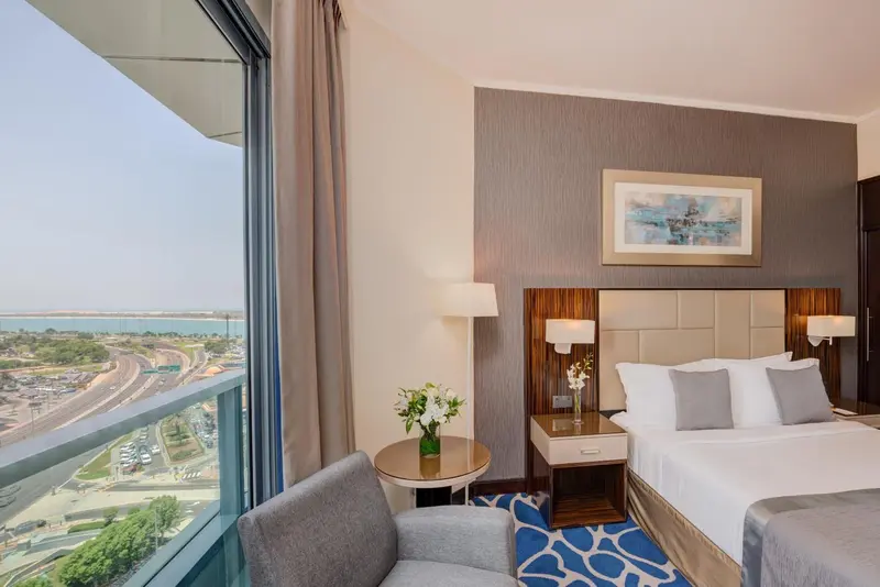 Chambre avec un lit double et une vue sur la mer depuis un balcon.