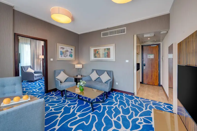 Un salon moderne avec canapés bleus et un tapis à motifs.