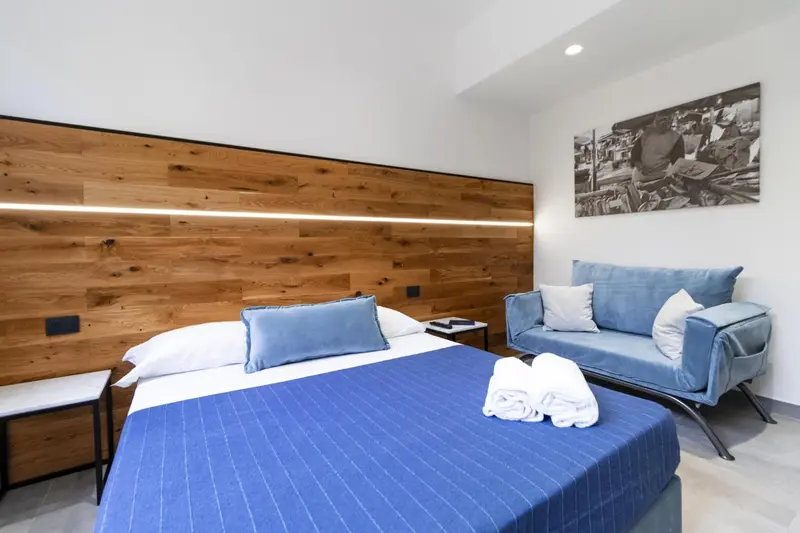 Une chambre lumineuse avec un grand lit et un canapé bleu.