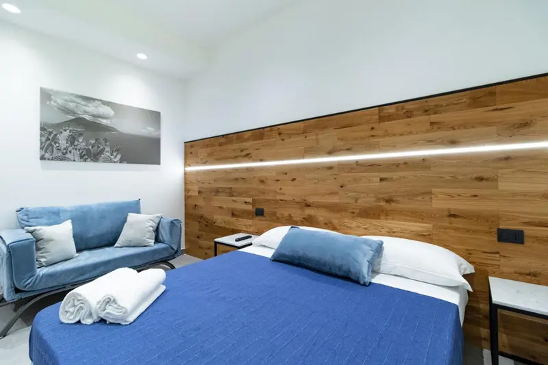 Une chambre lumineuse avec un canapé bleu et un grand tableau au mur.